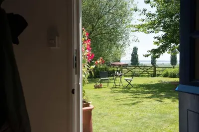 an open door to a yard with a table and chairs at The Wobbin, Remote, Comfort, Sea Views and the beautiful Essex Marshes in West Mersea