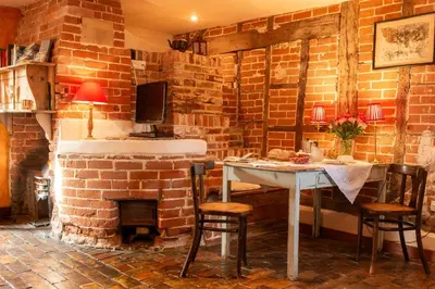 a dining room with a table and a brick wall at The Bakery a honeymooners favourite cosy stylish with lovely walks and pubs in Edwardstone