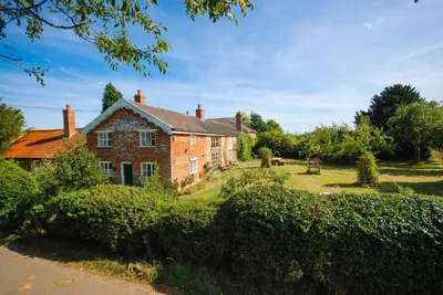 an old brick house with bushes in front of it at The Bakery a honeymooners favourite cosy stylish with lovely walks and pubs in Edwardstone