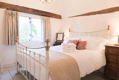 a bedroom with a white bed and a window at Water Cottage, a perfect ancient House in Suffolks prettiest tiny village in Kersey