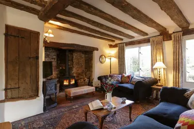 a living room with a couch and a fireplace at Water Cottage, a perfect ancient House in Suffolks prettiest tiny village in Kersey