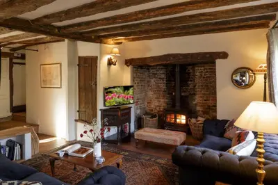 a living room with a couch and a fireplace at Water Cottage, a perfect ancient House in Suffolks prettiest tiny village in Kersey