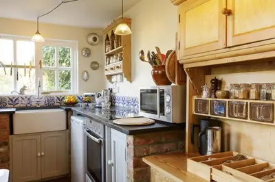 a kitchen with wooden cabinets and a counter top at Water Cottage, a perfect ancient House in Suffolks prettiest tiny village in Kersey