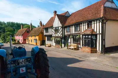 an oldfashioned tractor parked in front of a building at Water Cottage, a perfect ancient House in Suffolks prettiest tiny village in Kersey