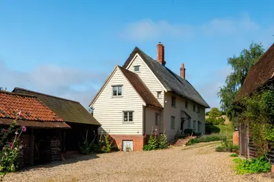 a large white house with a barn next to it at Mill Cottage set beside a Mill pond in a 70 acre Nature Reserve Bliss in Assington