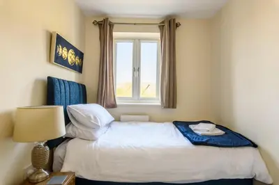 a small bedroom with a bed and a window at Charming & Spacious 3BR With Private Parking Near Ipswich in Ipswich