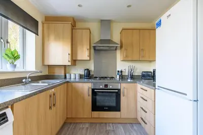 a kitchen with wooden cabinets and a stove top oven at Charming & Spacious 3BR With Private Parking Near Ipswich in Ipswich