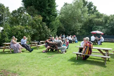 a group of people sitting at picnic tables in a park at The Compasses in Chelmsford