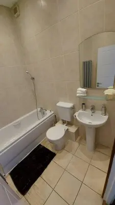 a bathroom with a sink and a toilet and a bath tub at Modern and spacious two bedroom apartment in Ipswich