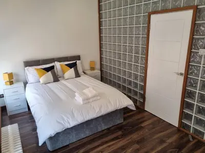 a bedroom with a large white bed with a door at Modern and spacious two bedroom apartment in Ipswich