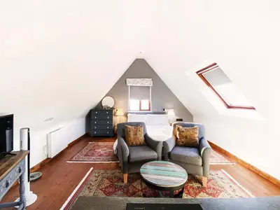 a attic room with two chairs and a bed at Little Dene Lodge by The Suffolk Cottage Collection in Pakenham