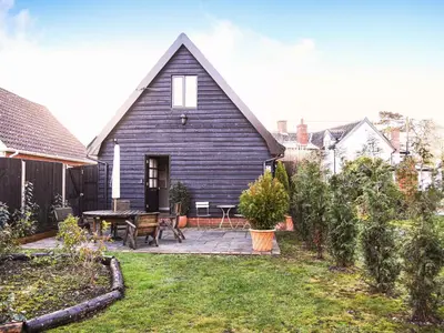a house with a black roof with a patio at Little Dene Lodge by The Suffolk Cottage Collection in Pakenham