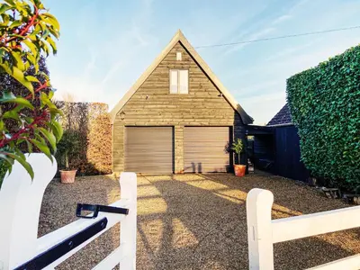 a house with a garage with a white fence at Little Dene Lodge by The Suffolk Cottage Collection in Pakenham