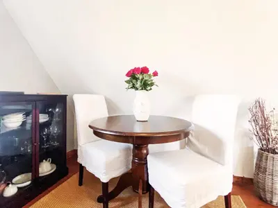 a table with two white chairs and a vase with flowers at Little Dene Lodge by The Suffolk Cottage Collection in Pakenham