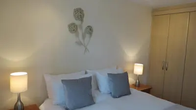 a bedroom with a bed with blue pillows and two lamps at Citystay Living- Warren Close in Cambridge