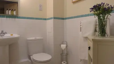 a bathroom with a toilet and a sink and a vase of flowers at Citystay Living- Warren Close in Cambridge