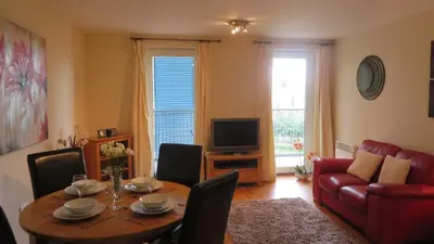 a living room with a table and a red couch at Citystay Living- Warren Close in Cambridge