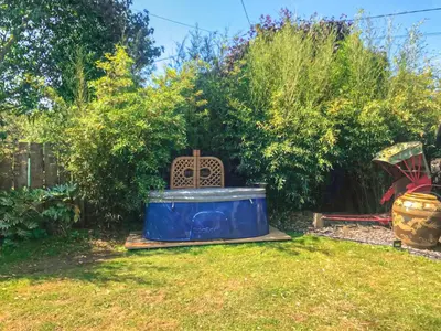 a garden with a blue tub and a chair in the grass at 1 Lamb Barn in Clacton-on-Sea
