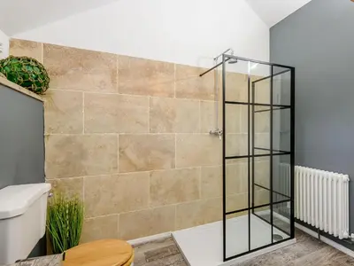 a shower with a glass door in a bathroom at 1 Lamb Barn in Clacton-on-Sea