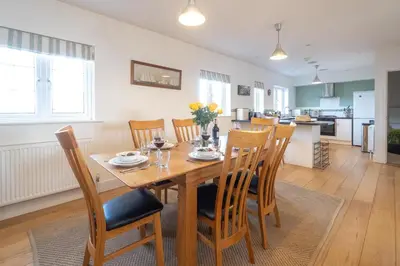 a dining room and kitchen with a wooden table and chairs at Gun Lodge - Aldeburgh Coastal Cottages in Aldeburgh