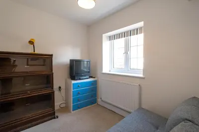 a living room with a tv on a dresser and a window at Gun Lodge - Aldeburgh Coastal Cottages in Aldeburgh