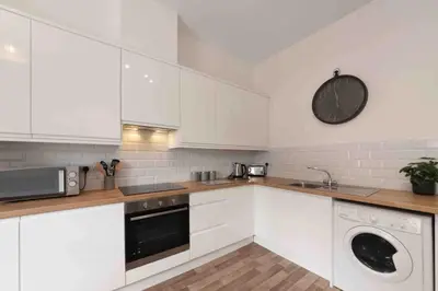 a kitchen with white cabinets and a dishwasher at Town center apartment in Bishops Stortford in Birchanger