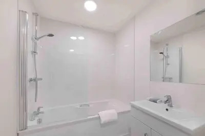 a white bathroom with a tub and a sink at Town center apartment in Bishops Stortford in Birchanger