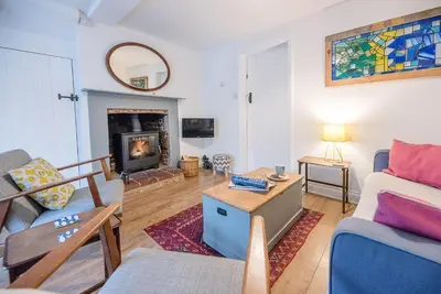 a living room with a couch and a fireplace at 2 Riverside Cottages, Yoxford in Saxmundham