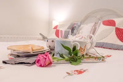 a table with cups and plates of food and flowers at 2 Riverside Cottages, Yoxford in Saxmundham