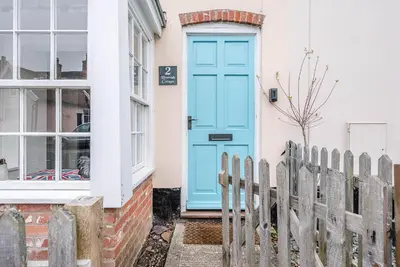 a blue door on a house with a fence at 2 Riverside Cottages, Yoxford in Saxmundham