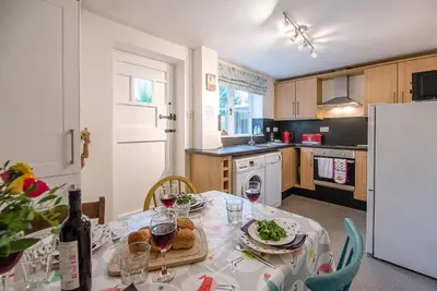 a kitchen with a table with food and wine glasses at 2 Riverside Cottages, Yoxford in Saxmundham
