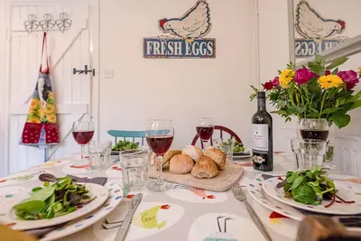 a table with plates of food and glasses of wine at 2 Riverside Cottages, Yoxford in Saxmundham