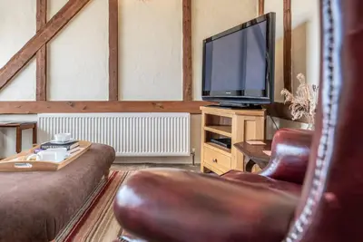 a living room with a couch and a television at Harvest Cottage, Valley Farm, Snape in Saxmundham