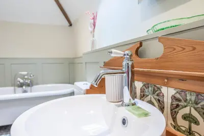 a bathroom with a white sink and a bath tub at Harvest Cottage, Valley Farm, Snape in Saxmundham