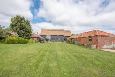 a large grass field in front of a building at Harvest Cottage, Valley Farm, Snape in Saxmundham