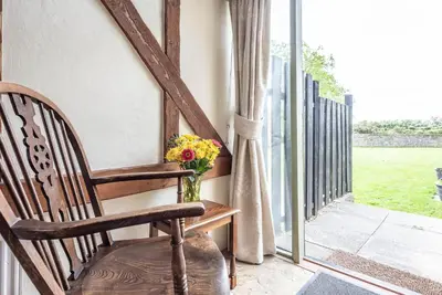 a rocking chair sitting on a porch with a window at Harvest Cottage, Valley Farm, Snape in Saxmundham