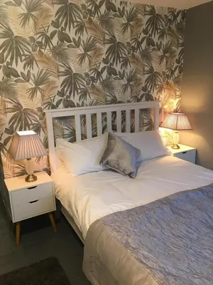a bedroom with a bed and two night tables with lamps at Stansted Airport Guest Rooms in Bishops Stortford