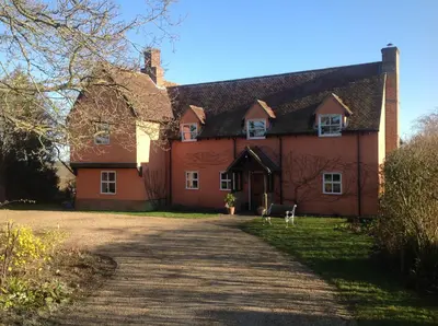 a large red house with a driveway in front of it at Dragonfly Cottage, Rattlesden in Rattlesden
