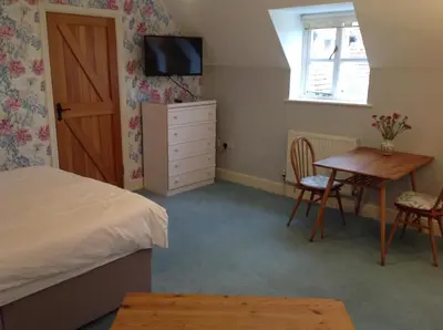 a bedroom with a bed and a desk and a table at Dragonfly Cottage, Rattlesden in Rattlesden