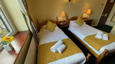 two beds in a hotel room with towels on them at Crown Hotel in Downham Market