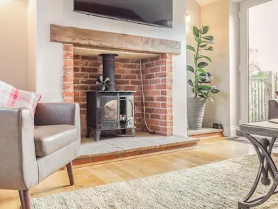 a living room with a brick fireplace with a television above it at The Croft in Thetford