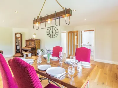 a dining room with a table and pink chairs at The Croft in Thetford