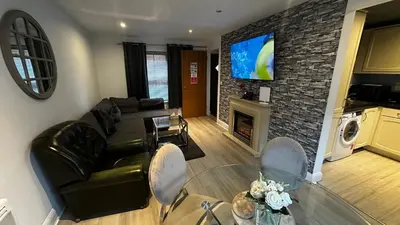 a living room with a black leather couch and a fireplace at One Bedroom Flat Town Centre Colchester in Colchester