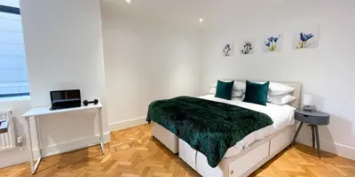 a bedroom with a bed and a laptop on a table at Modern Town Centre Apartment in Chelmsford
