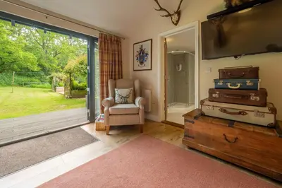 a living room with a tv and a chair and luggage at The Lodge, Wherstead in Wherstead