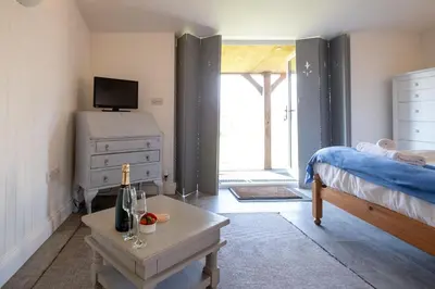 a bedroom with a bed and a table with a bottle of wine at East Green Farm Cottage - Studio Barn - Aldeburgh Coastal Cottages in Kelsale