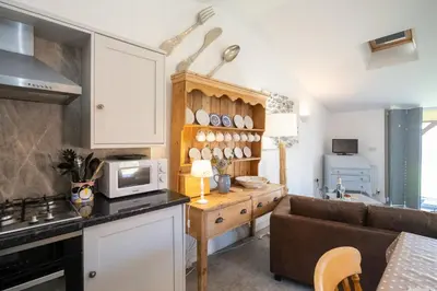 a kitchen and living room with a couch and a microwave at East Green Farm Cottage - Studio Barn - Aldeburgh Coastal Cottages in Kelsale