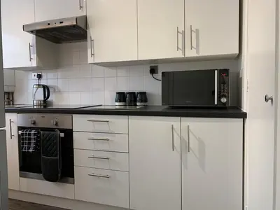 a kitchen with white cabinets and a black microwave at Modern Cosy Warm Home With Free Parking in Chelmsford