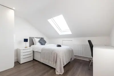 a white bedroom with a bed and a skylight at Townhouse for Professionals (5 Bedroom 5 Ensuite) in Ipswich