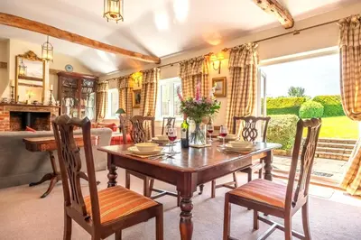 a dining room with a wooden table and chairs at Charming cottage in beautiful countryside with a boating lake - The Calf Pens in Ipswich